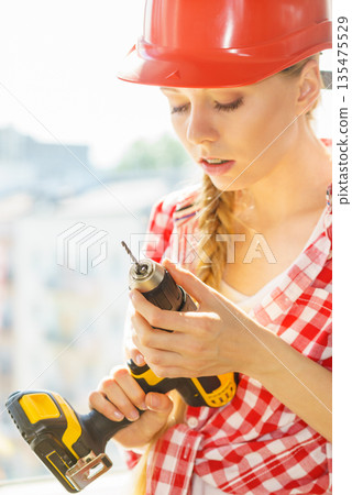 Young woman adjusting her drill doing Young woman adjusting her drill doing 135475529