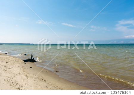 Sandy beach shoreline on Baikal lake with blue sky. Natural beauty of Olkhon island for travel and documentary. Summer landscape, vacation at Siberia. Sandy beach shoreline on Baikal lake with blue sky. Natural beauty of Olkhon island for travel and documentary. Summer landscape, vacation at Siberia. 135476364
