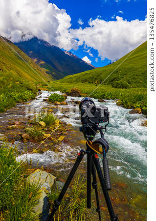 Camera on tripod capturing mountain stream in serene landscape 135476825