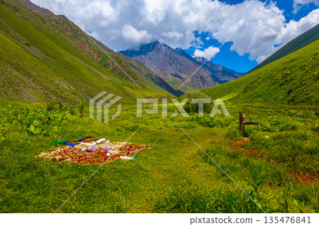 Picnic blanket with food and water tap in mountain valley Picnic blanket with food and water tap in mountain valley 135476841