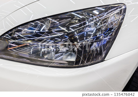 Shiny car headlight reflecting lights in modern garage 135476842
