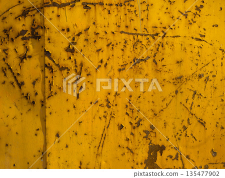 Weathered yellow steel surface with rust scratches and peeling paint 135477902