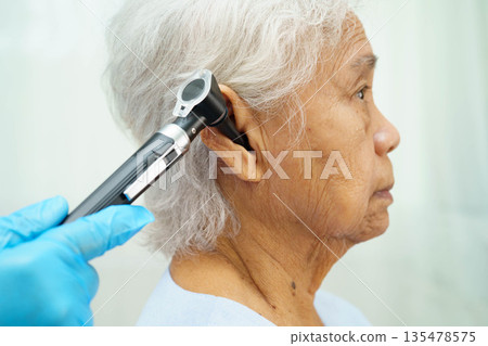 Otolaryngologist or ENT physician doctor examining senior patient ear with otoscope, hearing loss problem. Otolaryngologist or ENT physician doctor examining senior patient ear with otoscope, hearing loss problem. 135478575