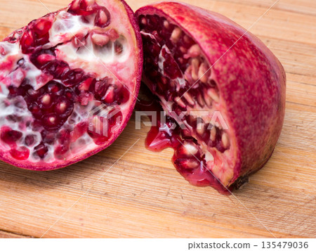 Cut ripe pomegranate on an old wooden table. Cut ripe pomegranate on an old wooden table. 135479036