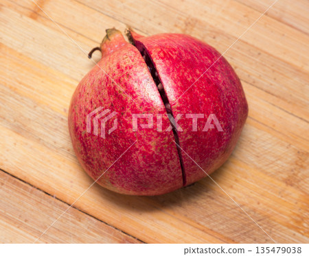 Cut ripe pomegranate on an old wooden table. Cut ripe pomegranate on an old wooden table. 135479038