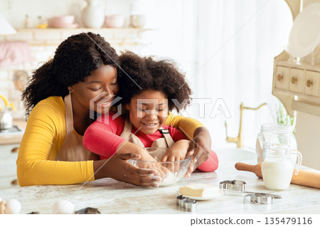 Happy Family In Kitchen. Black Mother And Little Daughter Preparing Dough Together, Loving African American Mom Teaching Her Child Cooking And Baking Homemade Pastry, Enjoying Spending Time With Kid 135479116
