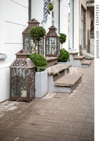 Decorative Metal Lanterns And Topiary Plants Placed Beside Elegant Outdoor Building Steps 135479193