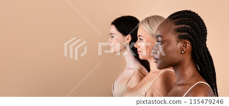 Profile Shot Of Three Beautiful Body Positive Multiracial Women. Side View Of Young Pretty Ladies With Different Skin Types And Appearances Posing Together Over Beige Studio Background, Free Space 135479246