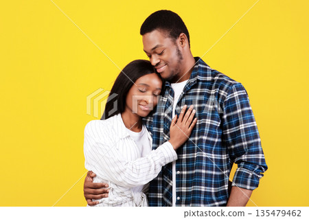 Romantic date, time together, family and relationship of couple. Millennial happy african american students guy and woman in casual, hugging, isolated on yellow background, empty space, studio shot 135479462