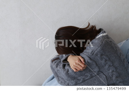 The back view of a depressed woman looking down. An image of worries and stress. The back view of a depressed woman looking down. An image of worries and stress. 135479499