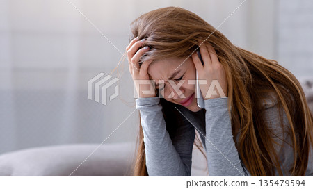 Sad young woman having conversation on mobile phone and crying at home. Millennial lady having difficult talk, hearing sad news, going through breakup or relationship problems 135479594