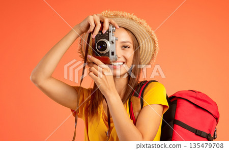 Active girl backpacker taking photos over yellow studio background, active resting concept 135479708