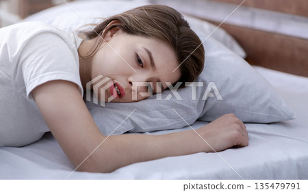 Young woman lying alone in her bed, mourning about loss of loved one, suffering from severe depression. Millennial lady feeling hopeless and desperate, having emotional stress or mental disorder Young woman lying alone in her bed, mourning about loss of loved one, suffering from severe depression. Millennial lady feeling hopeless and desperate, having emotional stress or mental disorder 135479791
