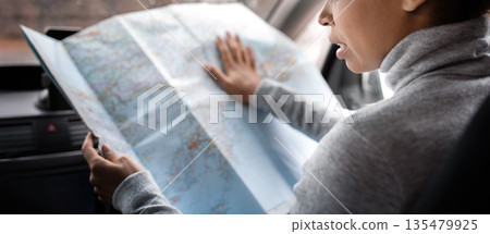 Search for road, found route and travel with friends in city. Busy beautiful cute young african american woman driver researching map in car and think, view of window with raindrops, copy space Search for road, found route and travel with friends in city. Busy beautiful cute young african american woman driver researching map in car and think, view of window with raindrops, copy space 135479925