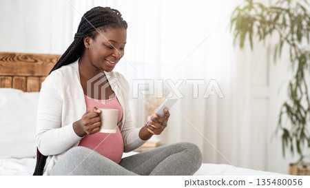 Leisure During Pregnancy. Black Expecting Lady Relaxing On Bed With Smartphone And Drinking Tea, Browsing Internet And Enjoying Hot Drink, Pregnant African Woman Resting In Bedroom At Home, Copy Space Leisure During Pregnancy. Black Expecting Lady Relaxing On Bed With Smartphone And Drinking Tea, Browsing Internet And Enjoying Hot Drink, Pregnant African Woman Resting In Bedroom At Home, Copy Space 135480056