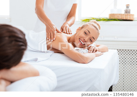 Wife Smiling To Husband During Couples Massage Relaxing And Enjoying Procedure Lying On Beds In Spa Beauty Salon. Relaxation Therapy, Rejuvenation And Wellness Concept. Selective Focus 135480146