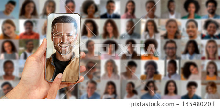 A smartphone held in a hand displays a facial recognition scan of a man, surrounded by a collage of various individual portraits, highlighting modern identification technology. A smartphone held in a hand displays a facial recognition scan of a man, surrounded by a collage of various individual portraits, highlighting modern identification technology. 135480201