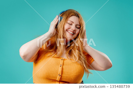 Overweight Pretty Woman Gets High, Listening Music With Headphones On Blue 135480739