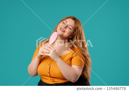 Body Positive Woman Singing, Dancing With Hair Brush Instead Microphone On Blue Body Positive Woman Singing, Dancing With Hair Brush Instead Microphone On Blue 135480778