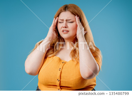 Plus Size Woman Touching Temples, Suffering From Headache, Pink Studio. Pain. Plus Size Woman Touching Temples, Suffering From Headache, Pink Studio. Pain. 135480799