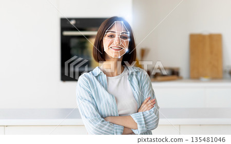 A woman stands confidently in a bright kitchen while a digital overlay showcases facial recognition technology. This reflects the integration of modern tech in daily life for identification purposes. A woman stands confidently in a bright kitchen while a digital overlay showcases facial recognition technology. This reflects the integration of modern tech in daily life for identification purposes. 135481046