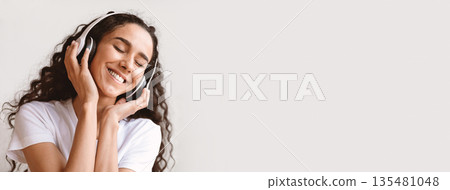 Joyful young brunette woman in headphones listening to music while resting on sofa at home, copy space. Happy lady with closed eyes enjoying beautiful music, stress relief, closeup portrait Joyful young brunette woman in headphones listening to music while resting on sofa at home, copy space. Happy lady with closed eyes enjoying beautiful music, stress relief, closeup portrait 135481048