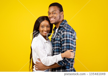 Romantic relationship of couple in love and quarantine covid-19 for two. Smiling african american guy and lady in casual, hugging at covid-19, isolated on yellow background, studio shot, copy space Romantic relationship of couple in love and quarantine covid-19 for two. Smiling african american guy and lady in casual, hugging at covid-19, isolated on yellow background, studio shot, copy space 135481049