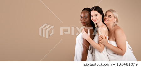 Beauty Diversity. Three Multi-Ethnic Women With Different Types Of Skin And Body Sizes Posing Wrapped In Towels Over Beige Background, Positive Young Females Embracing And Smiling At Camera 135481079