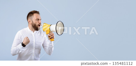 Agitated young man screaming into megaphone on grey studio background. Millennial public speaker with loudspeaker making announcement, advertising something, offering big sale or discount Agitated young man screaming into megaphone on grey studio background. Millennial public speaker with loudspeaker making announcement, advertising something, offering big sale or discount 135481112