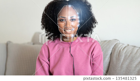 African American woman with curly hair smiles while a facial recognition system scans face for identification. This technology is becoming central to our daily interactions in various environments. African American woman with curly hair smiles while a facial recognition system scans face for identification. This technology is becoming central to our daily interactions in various environments. 135481325
