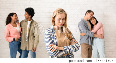 Relationships, love and loneliness. Sad young blonde student and two multiracial couples hugging in college or university, on white brick wall background, panorama, copy space, studio shot Relationships, love and loneliness. Sad young blonde student and two multiracial couples hugging in college or university, on white brick wall background, panorama, copy space, studio shot 135481397