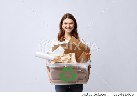 Recycling And Waste Sorting Concept. Smiling Young Woman Holding Plastic Box With Paper Garbage, Standing Over Light Background In Studio, Portrait Of Millennial Eco-Friendly Lady, Copy Space 135481400