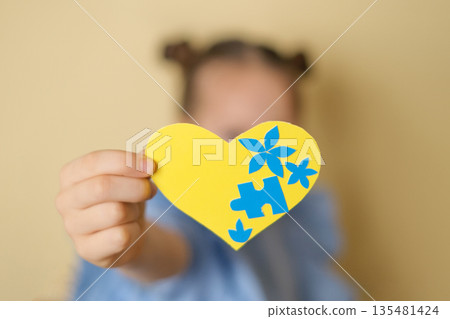 A close-up yellow heart decorated with blue flowers and puzzles. A symbol of awareness about down syndrome A close-up yellow heart decorated with blue flowers and puzzles. A symbol of awareness about down syndrome 135481424