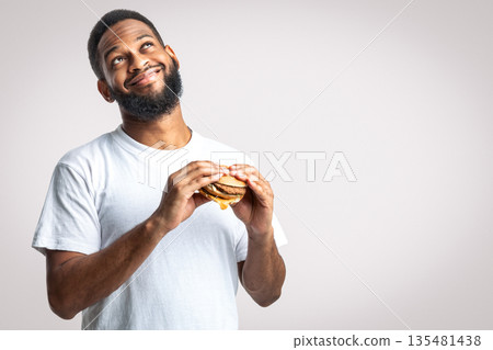 Cheat Meal. Happy Black Millennial Guy Smelling Tasty Burger Standing Dreamy Over White Studio Background. Junk Food Eater Concept. Nutrition And Overeating Habit 135481438