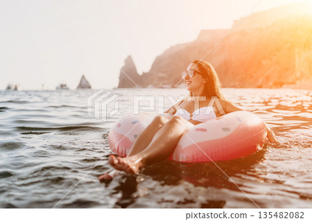 Vacation, Relaxation, Ocean. Young woman relaxing on inflatable donut in sunny ocean, enjoying summer holiday. 135482082