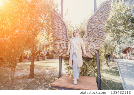 Woman Standing Underneath Angel Wings Sculpture Woman Standing Underneath Angel Wings Sculpture 135482118