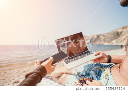 Laptop Beach Work Man - Working on a Laptop while Relaxing on a Beach. Laptop Beach Work Man - Working on a Laptop while Relaxing on a Beach. 135482124