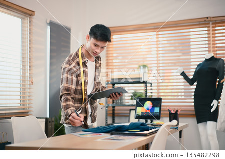 Fashion designer working in his home studio Fashion designer working in his home studio 135482298