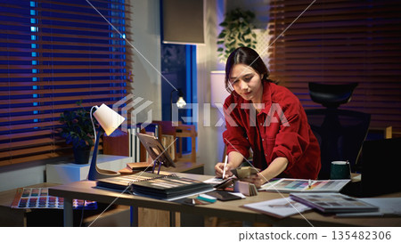 Architect interior designer working on new project in office. choosing materials and colors from samples Architect interior designer working on new project in office. choosing materials and colors from samples 135482306