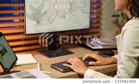 Architect Interior designer reviews architectural plans on a computer 135482368