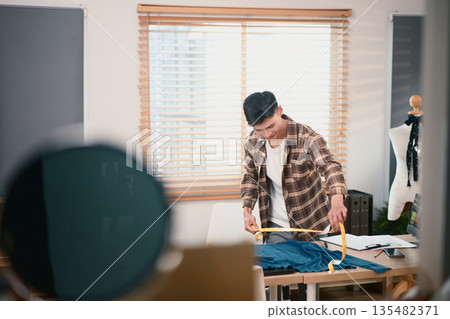 Fashion designer working in his home studio Fashion designer working in his home studio 135482371
