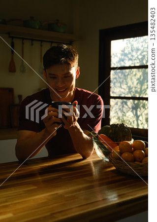 Man enjoying morning coffee in a warm kitchen, showing calm mood, relaxation, and a peaceful start to the day at home. Man enjoying morning coffee in a warm kitchen, showing calm mood, relaxation, and a peaceful start to the day at home. 135482403