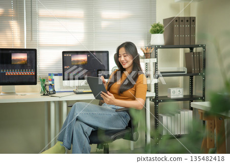 Professional female video editor editing video on his digital tablet in home office studio Professional female video editor editing video on his digital tablet in home office studio 135482418