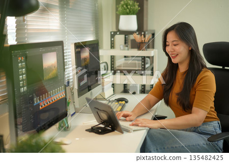 Professional female video editor editing video on his digital tablet in home office studio 135482425