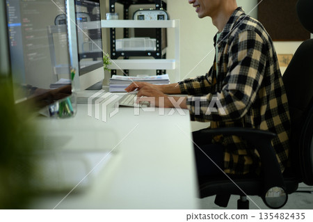 A Man IT Specialist in home office workplace with coding language program on computer A Man IT Specialist in home office workplace with coding language program on computer 135482435