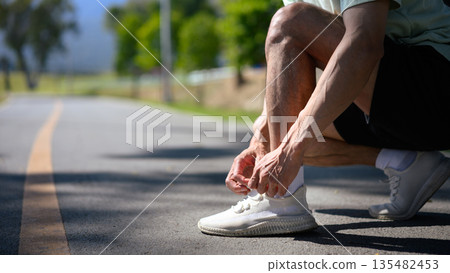 Closeup runner man tying lace running shoes in the park 135482453