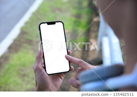 Man using smartphone in park with empty screen 135482511