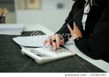 Business accounting concept, Business woman using calculator, budget and loan paper in office Business accounting concept, Business woman using calculator, budget and loan paper in office 135483565