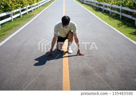 Runner in starting position on an empty road, symbolizing a fresh start, motivation, and determination for new year fitness goals. Runner in starting position on an empty road, symbolizing a fresh start, motivation, and determination for new year fitness goals. 135483580