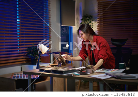 Architect interior designer working on new project in office. choosing materials and colors from samples Architect interior designer working on new project in office. choosing materials and colors from samples 135483618